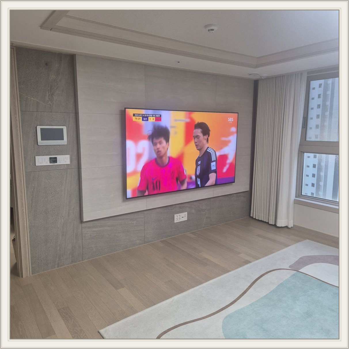 밝은 회색 아트월과 시청 공간 — 밝은 몰딩과 TV 아래 전원 위치가 같이 나타납니다
