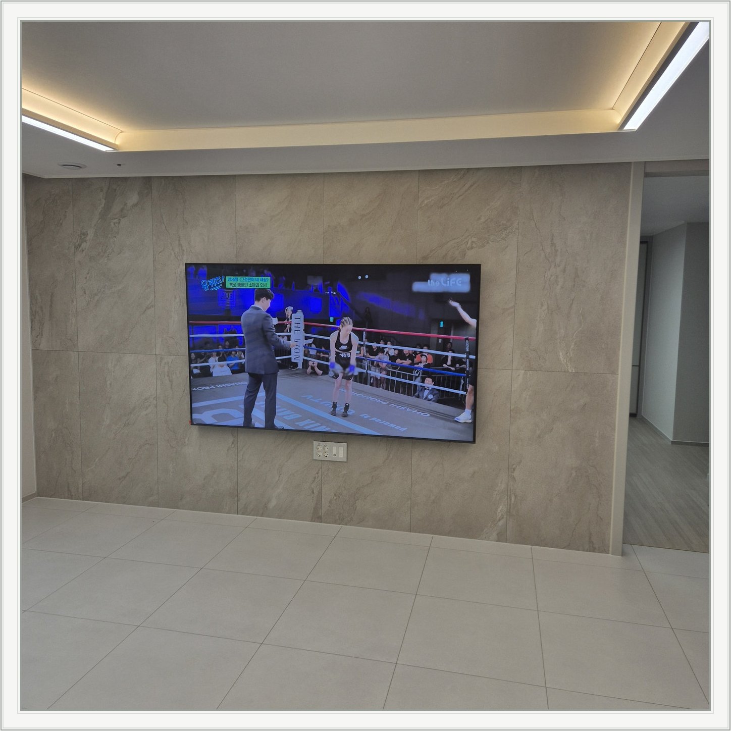 돌무늬 패널과 대형 TV — TV 아래 콘센트 패널이 드러나는 구도입니다