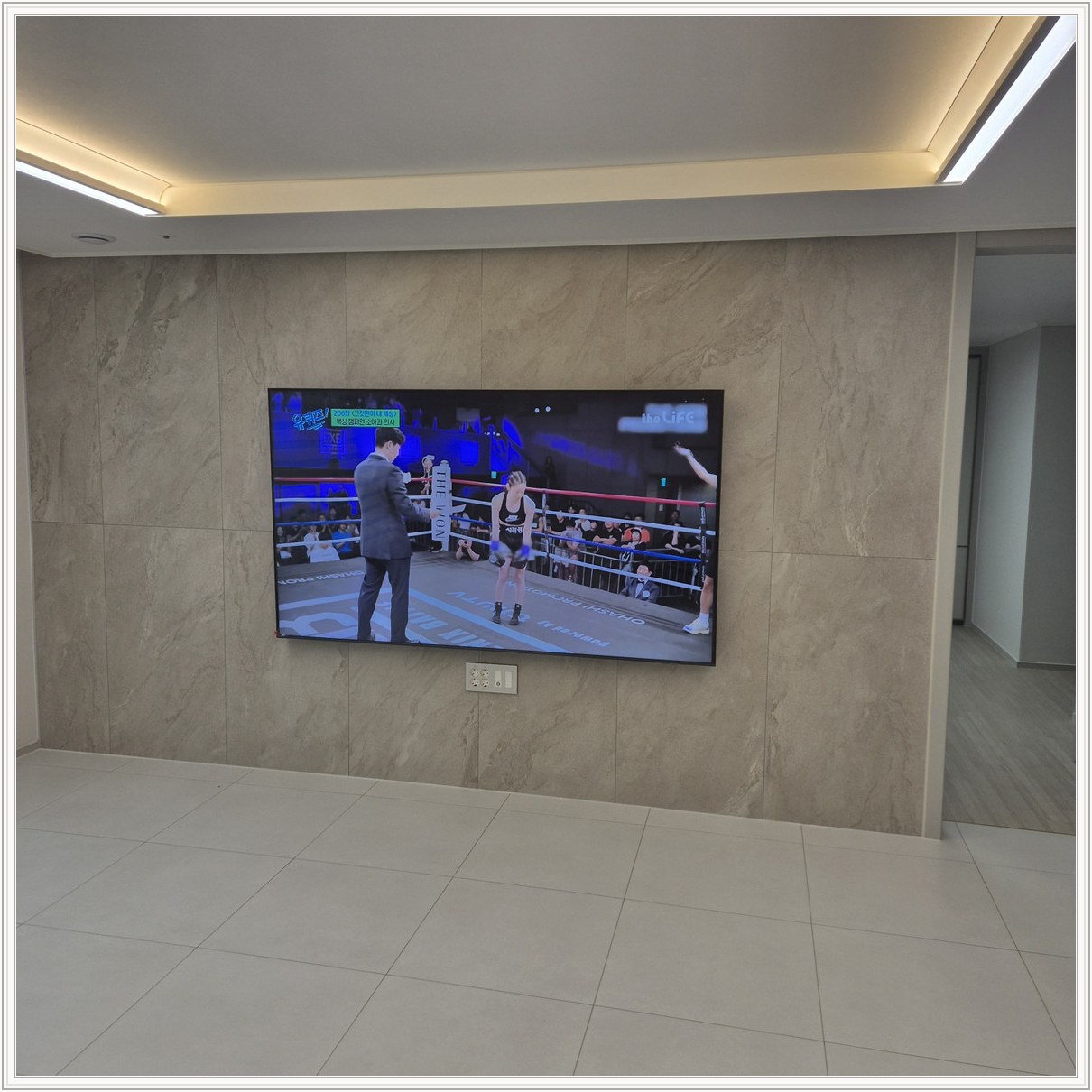 돌무늬 패널과 대형 TV — TV 아래 콘센트 패널이 드러나는 구도입니다