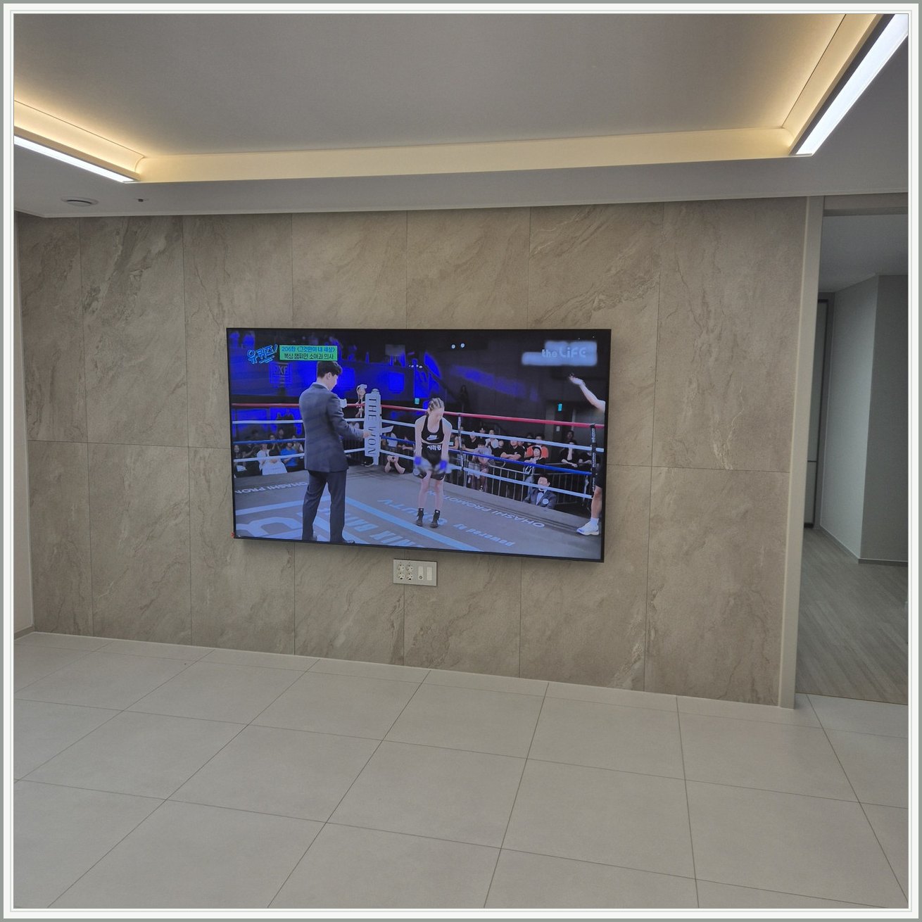 돌무늬 패널과 대형 TV — TV 아래 콘센트 패널이 드러나는 구도입니다